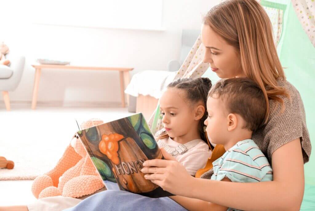 woman reading a book to two children