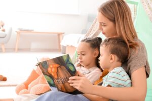 woman reading a book to two children