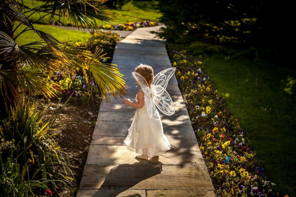 girl wearing white fairy costume standing on wooden pathway