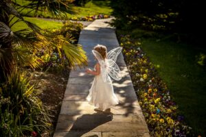 girl wearing white fairy costume standing on wooden pathway